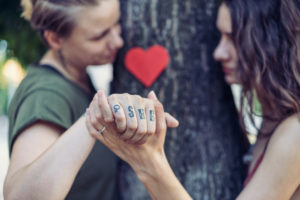 iStock 867753736 300x200 - Young female couple holding hands. Focus on grasping hands in the foreground.